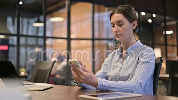年轻女性在工作中使用智能手机视频的预览图