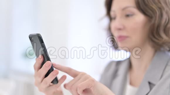 老妇人在模糊中使用智能手机视频的预览图