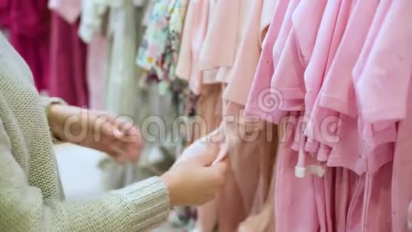 年轻女子在儿童服装店为孩子挑选衣服视频的预览图