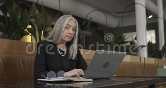 成熟优雅的女性首席执行官在笔记本电脑上观看商业演示美丽的中年人侧景视频的预览图