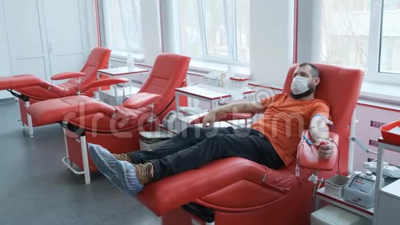 戴面具的捐献者躺在沙发上人捐献静脉血献血概念视频的预览图