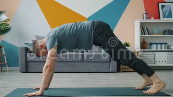 胡须男做平衡瑜伽练习动作缓慢在家里锻炼视频的预览图
