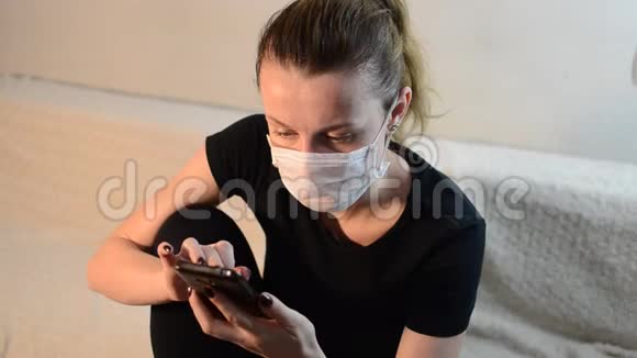 戴着医用口罩的年轻女孩正在智能手机上输入一条信息视频的预览图