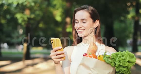 近距离观看欢快的女孩浏览网同时拿着纸袋与食品购物有魅力的女人视频的预览图