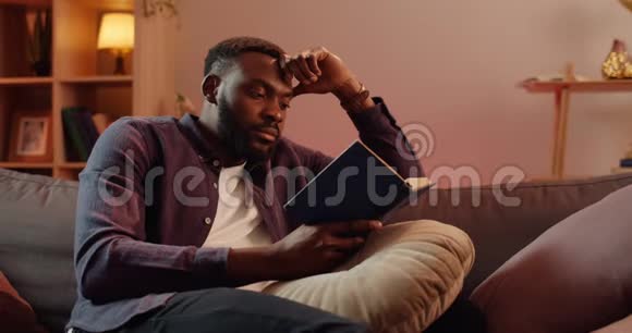 一个英俊的非洲男人在客厅里坐在沙发上用手斜着头年轻人在空闲时间视频的预览图