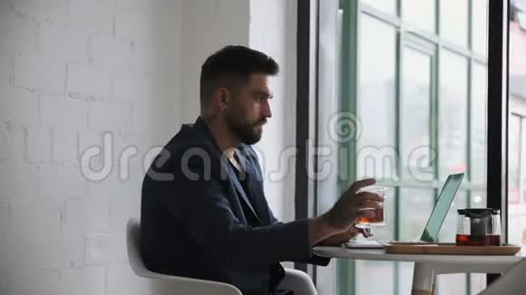 一个长着大胡子戴着耳环的男人在咖啡馆里工作视频的预览图