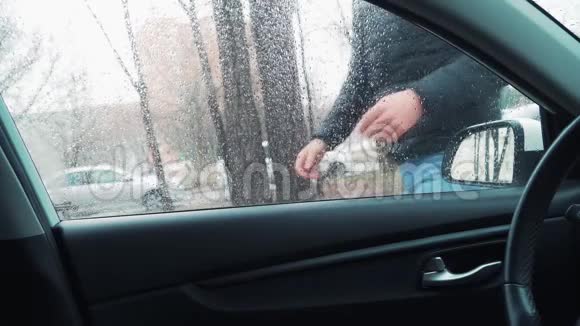 一个年轻人打开司机门上了他的车街上下着雨视频的预览图