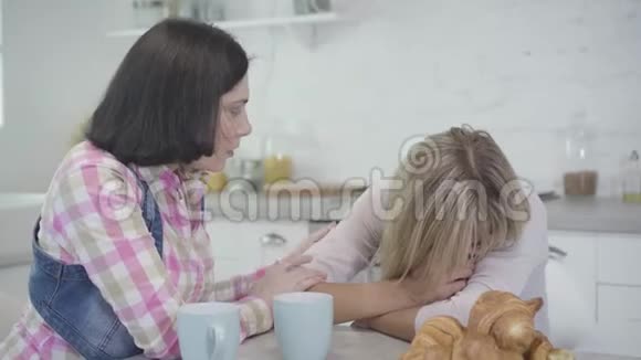 穿着衣服的白种人女人哭着她的黑发朋友让她平静下来女人友谊支持生活方式视频的预览图