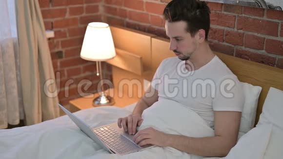 注意力集中的年轻人会被床上的笔记本电脑吓倒视频的预览图