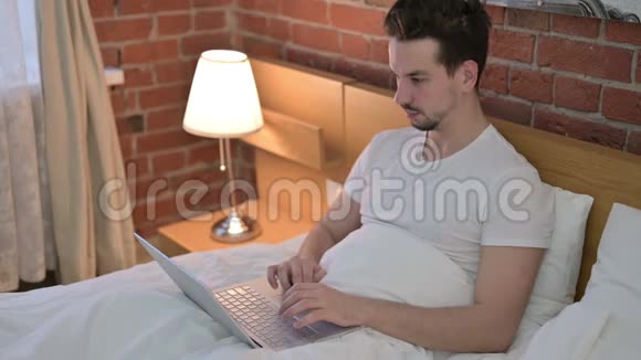 在床上工作时脖子疼的年轻人视频的预览图
