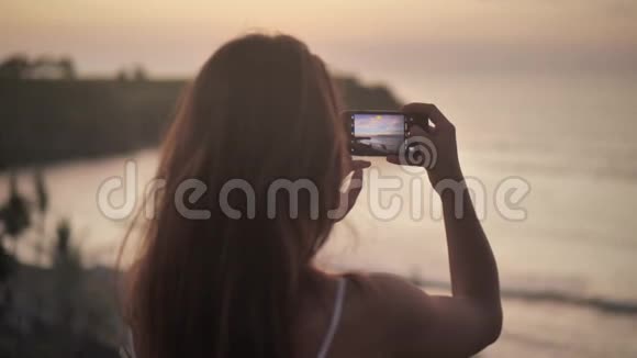 年轻的女人手拿智能手机做自然摄影年轻旅游女用手机拍照视频的预览图