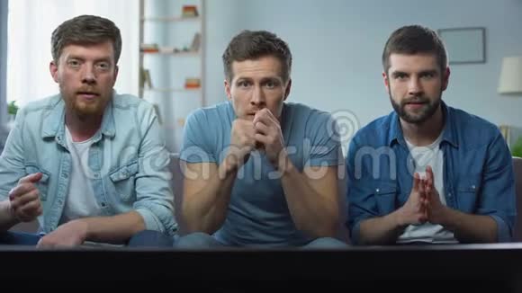 三个最好的朋友在家看电视上的体育比赛玩得很开心视频的预览图