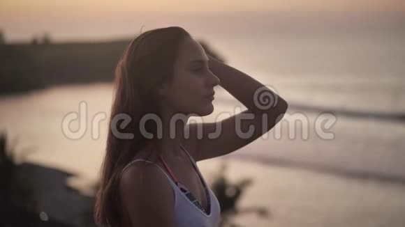 迷人的女孩站在悬崖上她享受日落祈祷4k视频的预览图