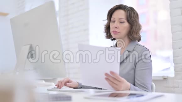 创造性的老妇人在文件和桌面上工作视频的预览图