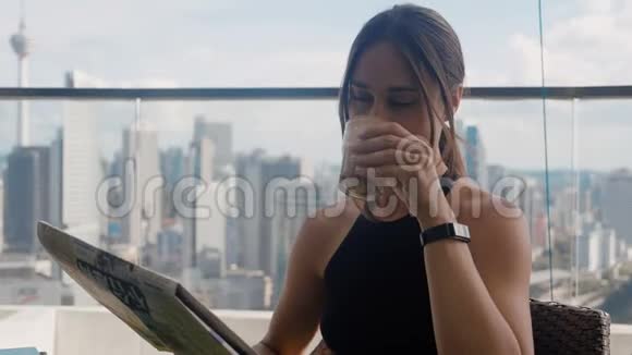 忙碌的女商人坐在咖啡馆里喝着拿铁看着报纸摩天大楼背景4K视频的预览图