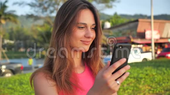 特写一个穿着粉红色短衬衫的迷人女孩的肖像她站在背景中的网站棕榈可爱是视频的预览图