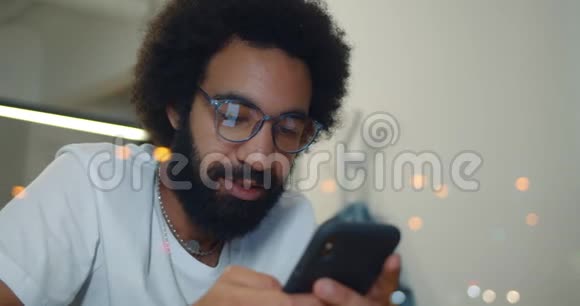 戴眼镜的胡子男看着智能手机屏幕和滚动新闻提要在30多岁的时候用他的视频的预览图