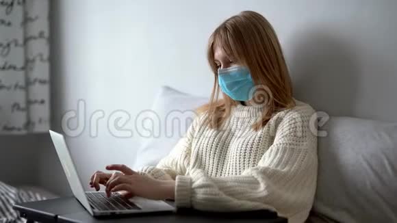 戴着医用口罩在家拿着笔记本电脑工作的年轻女性视频的预览图