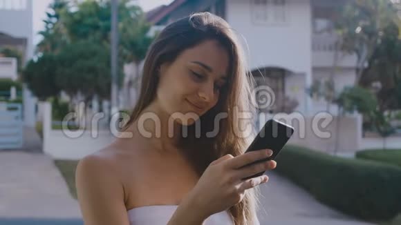 一位年轻的女性站在路边点击一部智能手机她笑得很甜视频的预览图