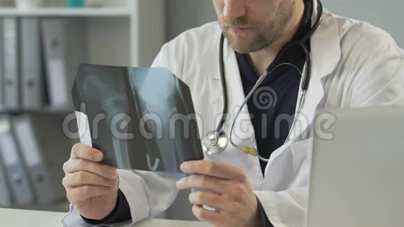 有经验的骨科医生检查腿部x光并在笔记本电脑上咨询病人视频的预览图