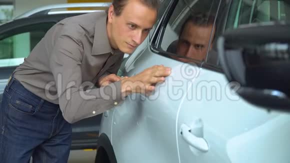 一个男人在汽车经销店里检查一辆车视频的预览图