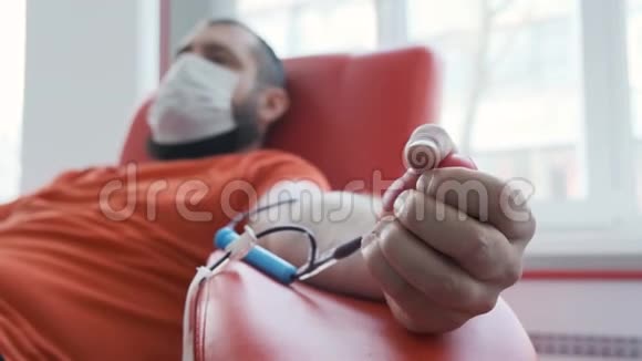 在采集静脉血的过程中用面罩紧紧抓住红色应激球的离焦献血者血液视频的预览图