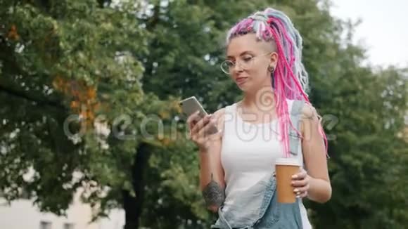 可爱的女孩朋克在公园里带着智能手机走到户外然后拿出咖啡视频的预览图