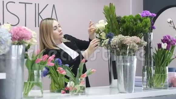 鲜花店美丽的少女小心地把花调在花瓶里视频的预览图