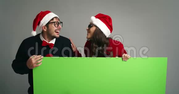 奈尔德夫妇指着圣诞服装上的绿色屏幕标语牌视频的预览图