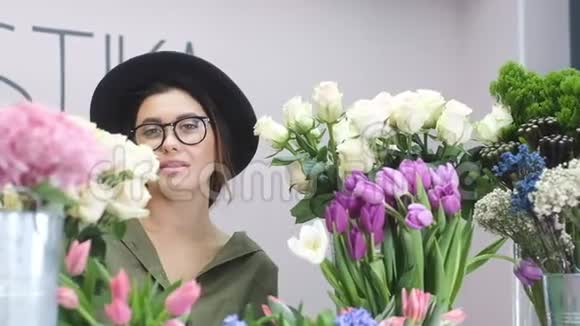 一个戴着帽子的美丽的欧洲女孩在花店里的画像视频的预览图