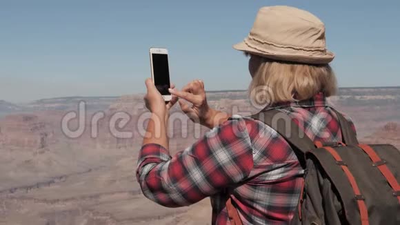 徒步女在大峡谷悬崖边上的手机上拍照视频的预览图