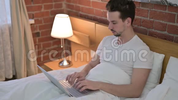 在床上工作时头痛的年轻人视频的预览图