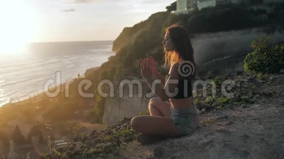 平静的女孩做瑜伽冥想日落海岸慢动作巴厘岛梅拉斯蒂海滩4k视频的预览图