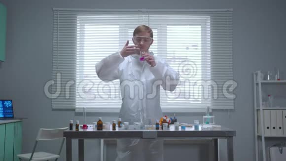 前面看穿着防护工作服的人拿着带有化学物质的管子在实验室里嗅了嗅视频的预览图