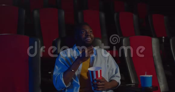 激动人心的刺激器开始保持座位而电影已经开始年轻的非洲人一边吃爆米花一边看电影视频的预览图