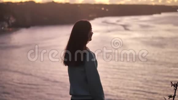特写一幅美丽的年轻女子的肖像仰起双臂随风吹起头发在宁静的海边享受着视频的预览图