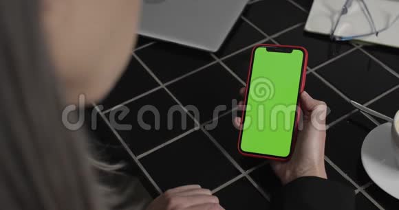 中年妇女使用现代智能手机和看屏幕的后视图把女人的手拿着电话视频的预览图