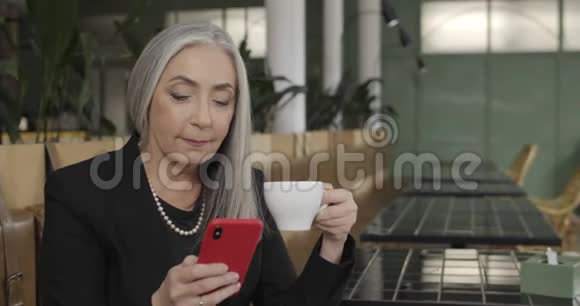 下班休息时把坐在咖啡桌上的漂亮的老商人关起来老年灰发女士视频的预览图