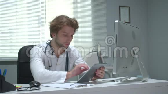医生坐在医院的一张桌子旁用平板电脑工作视频的预览图
