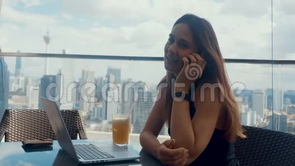 自信的商务女性坐在户外咖啡馆里她在打电话午休时间大型商业区视频的预览图