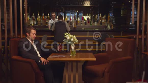 男人坐在咖啡馆的一张桌子旁通过电话中的视频链接交谈视频的预览图