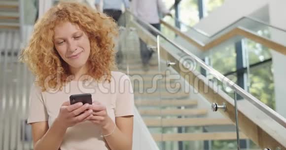 女性上班族使用智能手机站在现代办公室的大厅里女性企业工人冲浪网视频的预览图