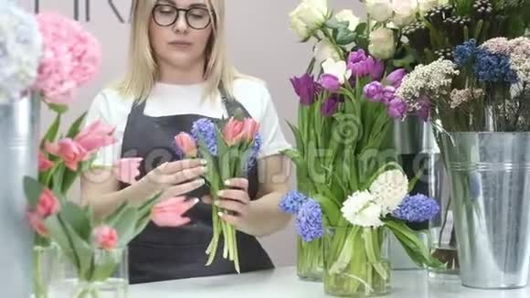 年轻的女人做了一束新鲜的郁金香商店里出售植物视频的预览图