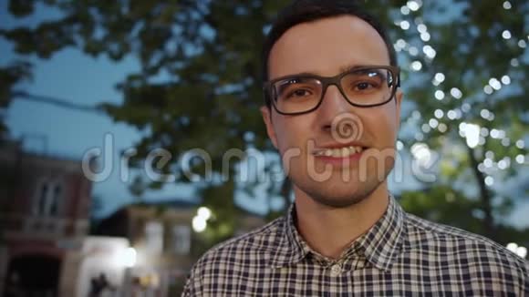 一幅迷人的商人戴眼镜晚上在城市里看相机的画像视频的预览图