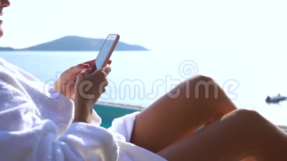 美丽的微笑比基尼女人在游泳池海滩使用智能手机女孩在手机上发短信和上网视频的预览图
