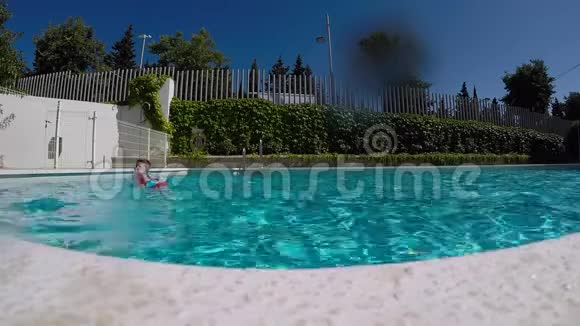 年轻男子跳着蓝色清澈的游泳池视频的预览图