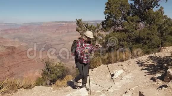 成熟的女人背着背包爬上大峡谷的山岩徒步旅行视频的预览图
