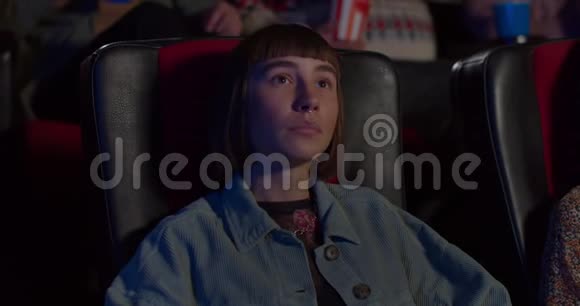 千禧女孩在电影院上演迷人电影的前景带着鼻环咀嚼爆米花的嬉皮士吉尔视频的预览图