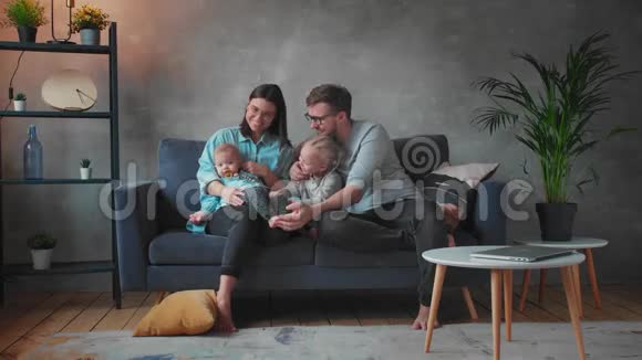 年轻的家庭在沙发上一起玩幸福的家庭家庭舒适视频的预览图