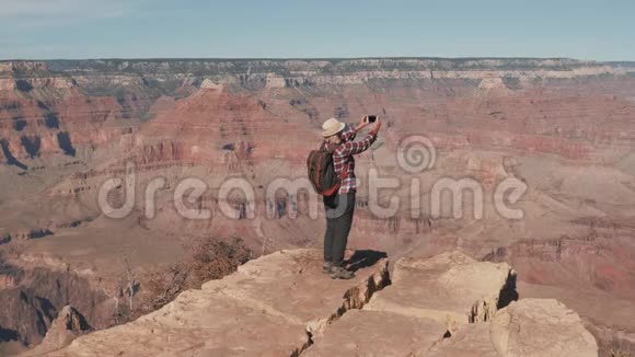 徒步女在大峡谷岩石边缘的智能手机上拍照视频的预览图